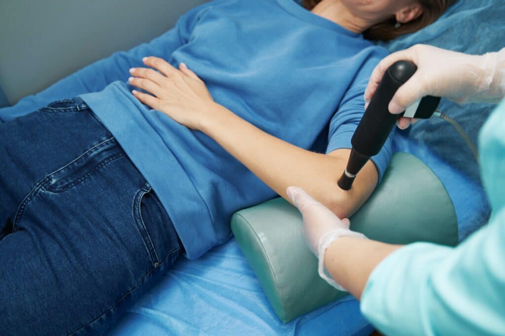 Doctor performing shockwave therapy procedure with pain relief device